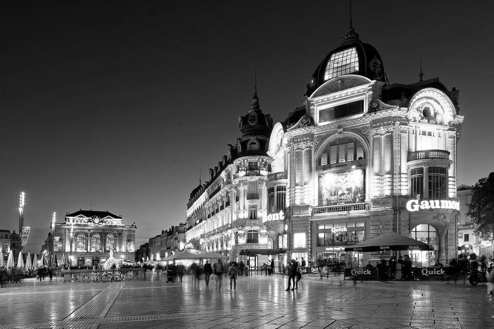 Photo de nuit de la Place de la Comédie à Montpellier. En 1er plan le cinéma Gaumont Comédie et au fond l'Opéra Comédie.